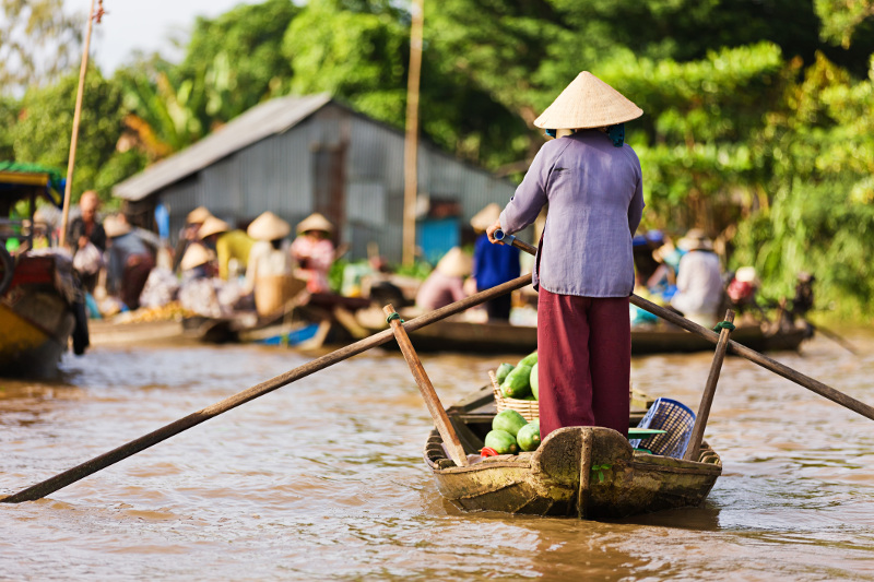 Woman steers long boat down Mekong River Delta