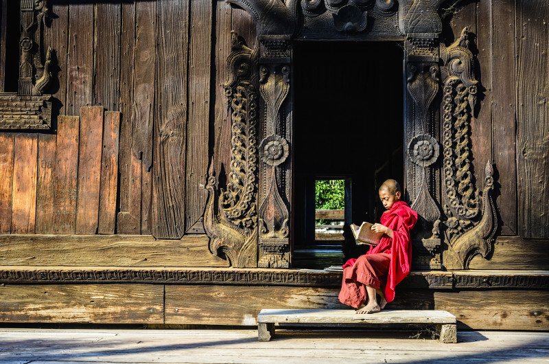 Monk sits on ornate temple steps in Myanmar
