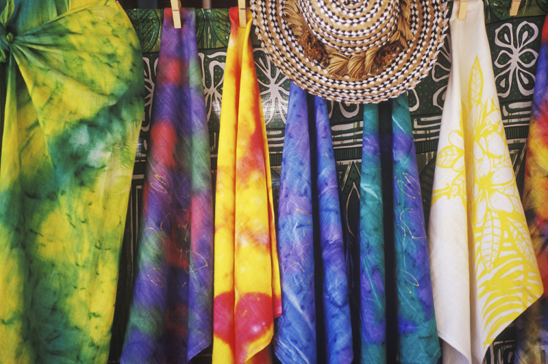 Colourful sarongs and a woven hat at a market stall
