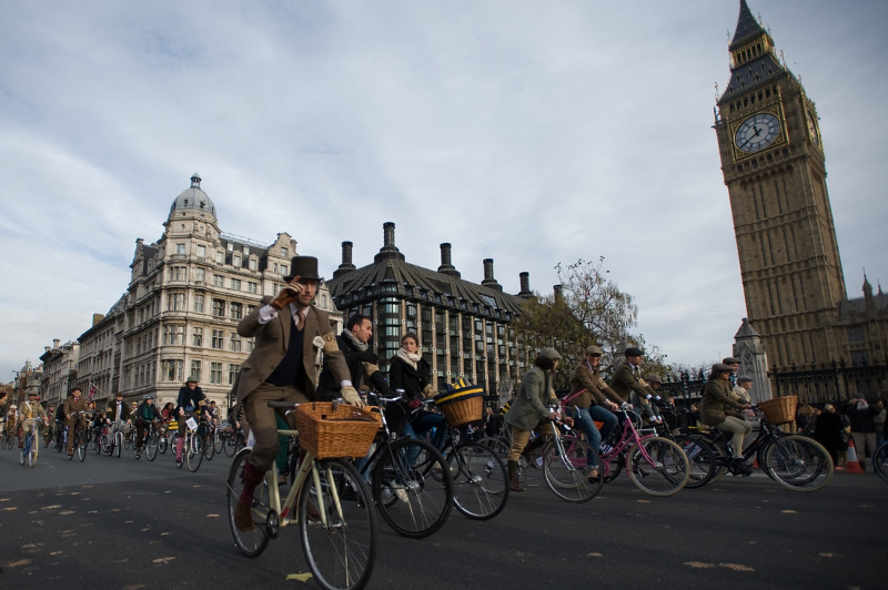 People in old fashioned costume cycle past Big Ben