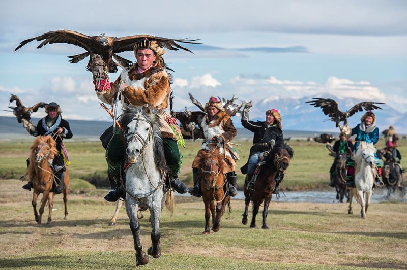 Kazakh Mongolian Cavalry Golden Eagle Hunter across the river in Altai Mountains Kazakh Mongolian Cavalry Golden Eagle Hunter across the river in Altai Mountains