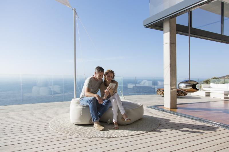 Couple on seaside deck look at tablet