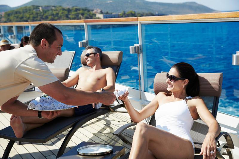 Staff hands woman towel on deck of cruise ship Seabourn Odyssey